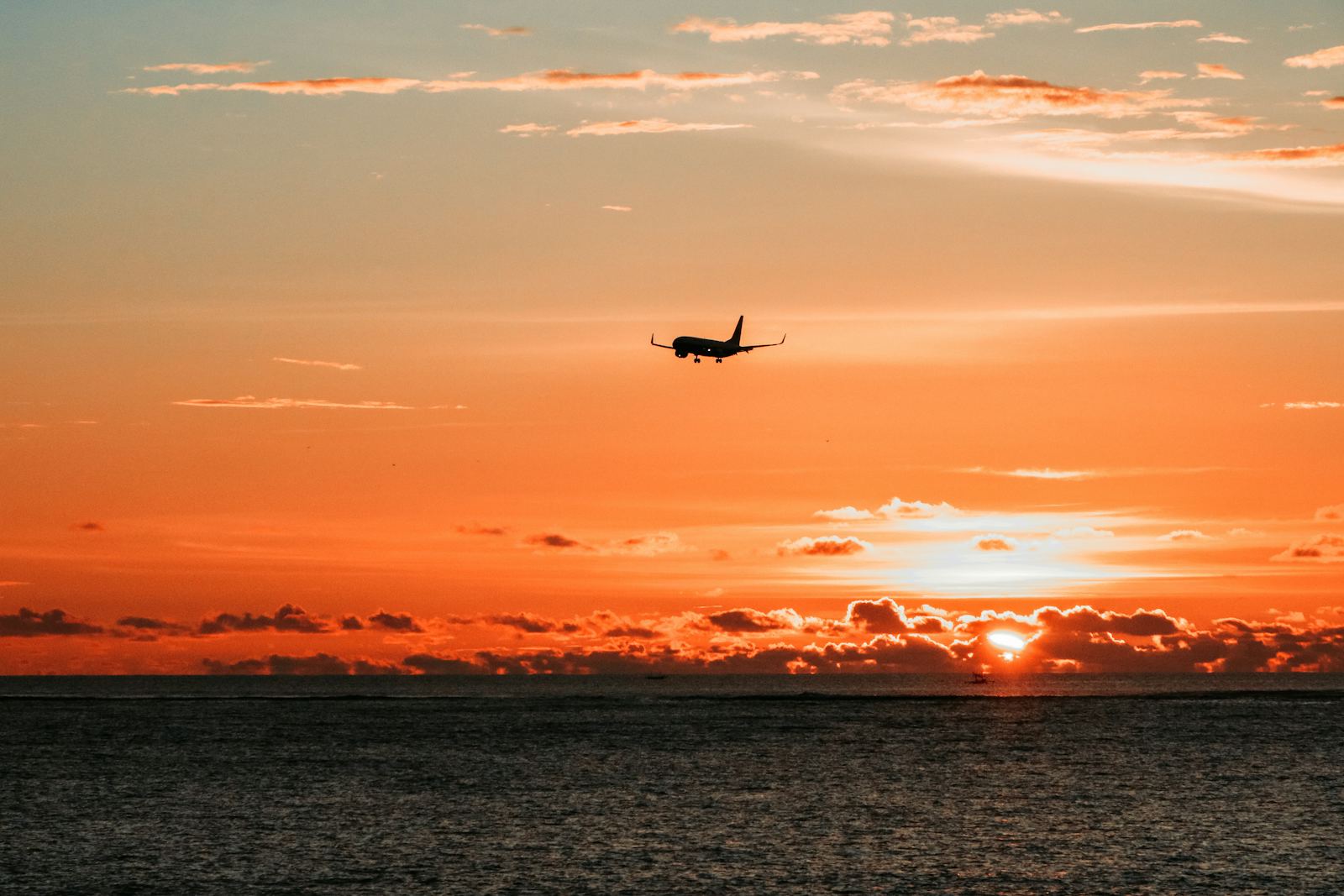 Airplane departing at sunset over the ocean
