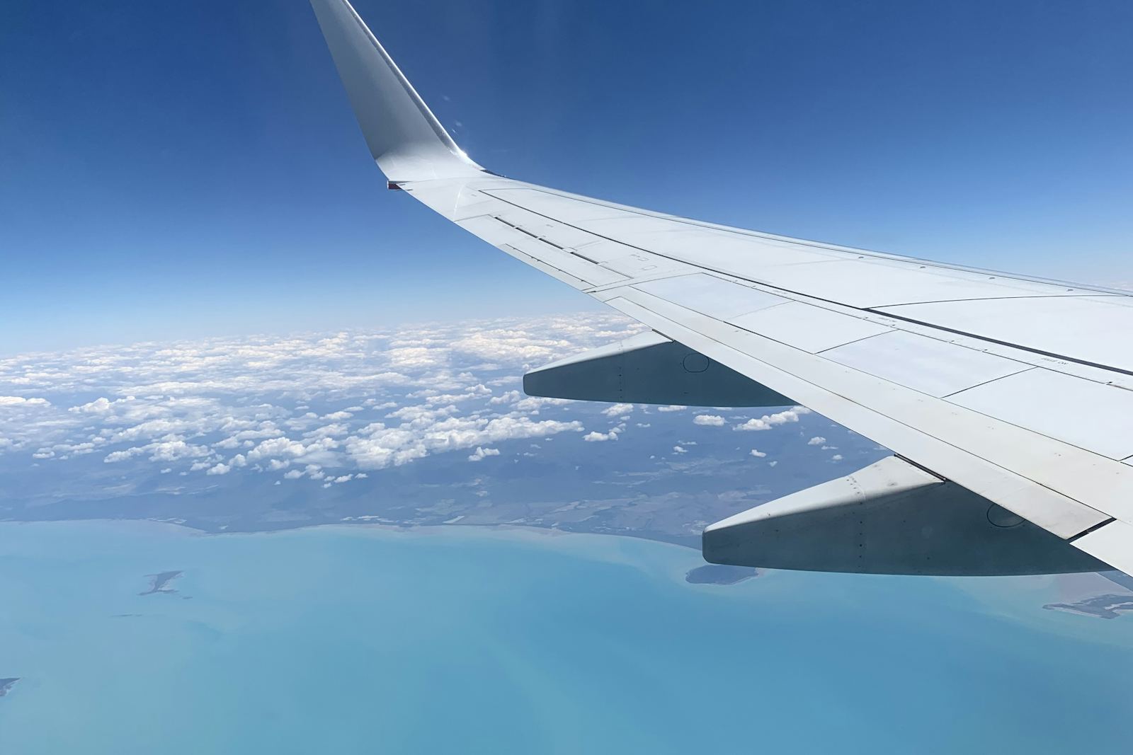 View over a turquoise coastline from an airplane wing